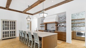 A spacious kitchen with a large island, wooden beams, and modern appliances.