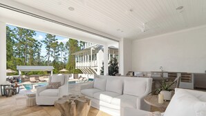 A spacious living area with a white sofa, a coffee table, and a poolside setting with outdoor furniture.
