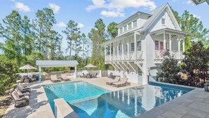 A large house with a swimming pool, outdoor furniture, and a covered patio area.