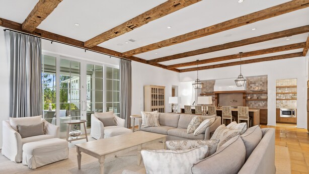 A spacious living room with a large sectional sofa, a coffee table, and a fireplace. There is a dining area with a table and chairs, and a kitchen with a microwave.