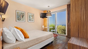 Een hotelkamer met een bed, een televisie, een balkon met uitzicht en een houten kast.