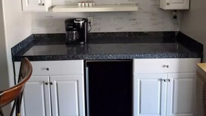 A kitchen with white cabinets, a black countertop, and a coffee maker.
