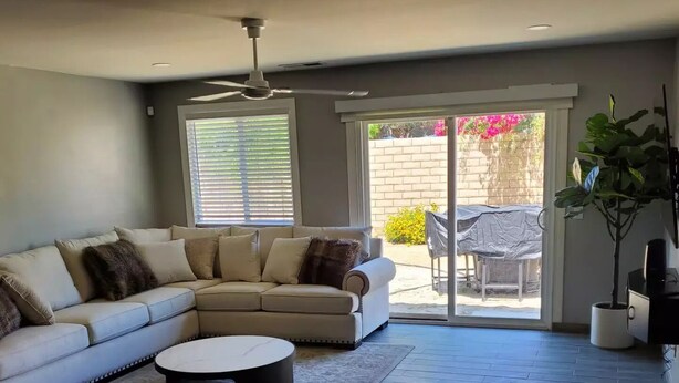 A modern living room with a sectional sofa, a coffee table, and a large window with blinds.
