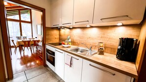 Een moderne keuken met witte kastjes, een roestvrijstalen spoelbak en een koffiezetapparaat.