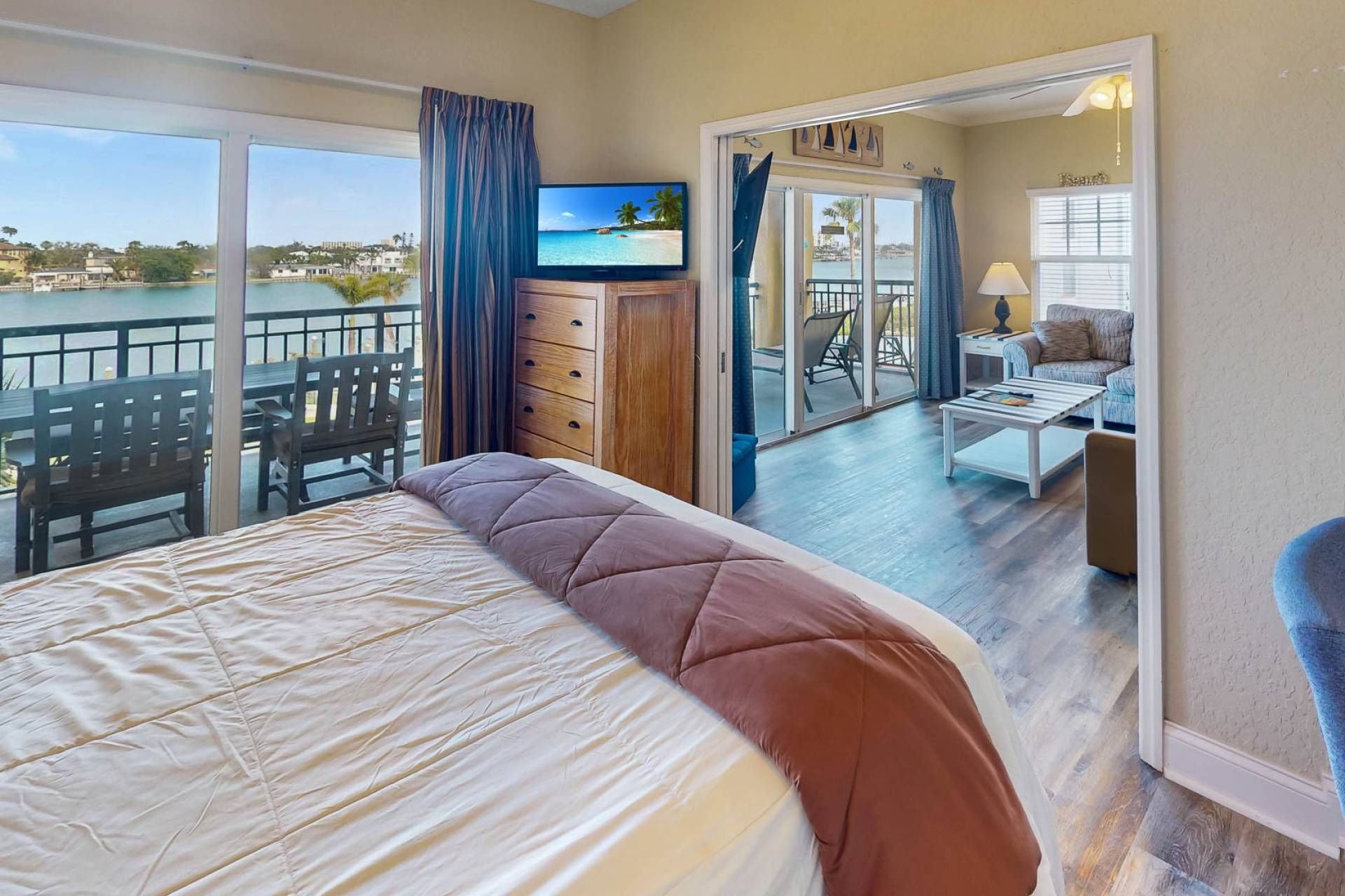 Habitación de hotel con cama, televisión, balcón con vista al mar y zona de estar con mesa y sillas.