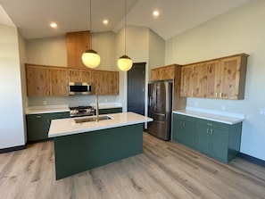 Enjoy cooking in this well-equipped kitchen with a central island, stainless steel sink, and modern appliances.