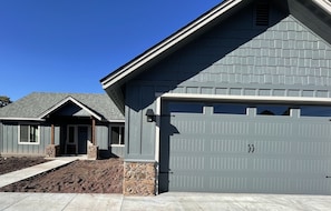 Stylish home with a modern design, featuring a garage door and a well-manicured lawn.