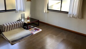 Et værelse med sofa, et lille bord, en måtte og et vindue med gardiner.