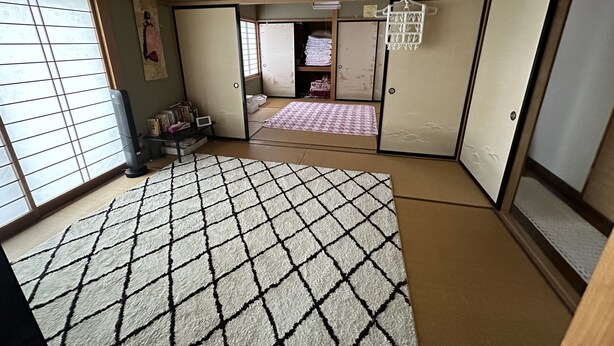 Et traditionelt japansk rum med tatami-gulv, skydedøre og en futon-madras.