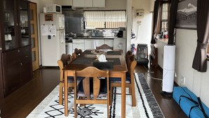 Et kompakt køkken med hvide skabe, en mikrobølgeovn og en komfur. Der er et spisebord med stole og en måtte.
