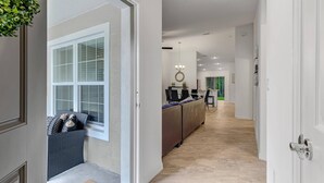 A modern interior with a dining area, a sofa, and a hallway leading to a kitchen.