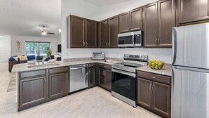 A modern kitchen with dark wood cabinets, stainless steel appliances, and a granite countertop.