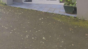 Un edificio residenziale con patio coperto, porta scorrevole in vetro e una pianta in vaso.