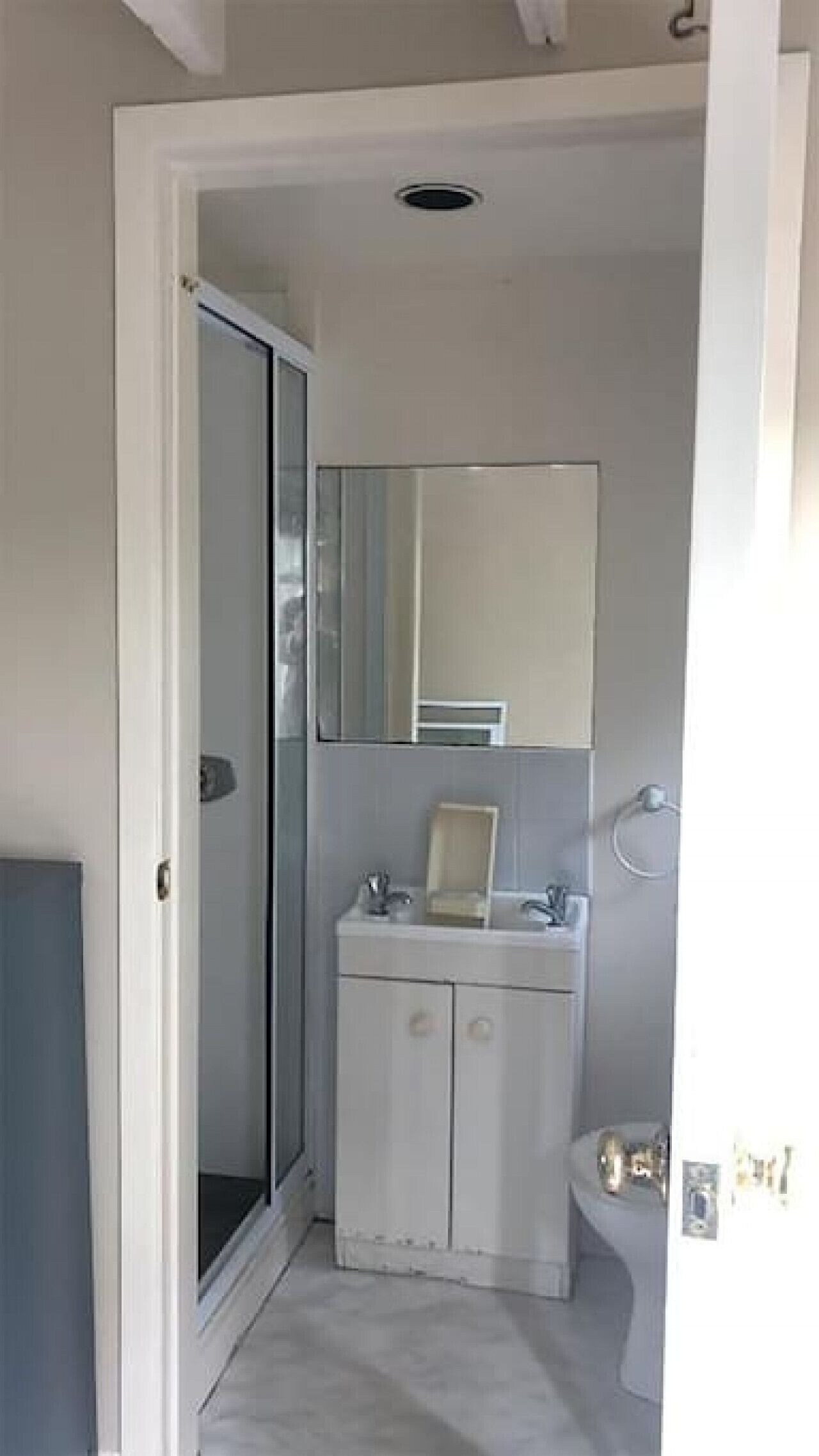 A bathroom with a white sink, mirror, and toilet.