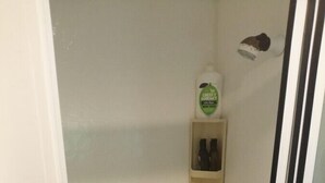 Un bagno piccolo con doccia, WC e uno scaffale con articoli da toilette.