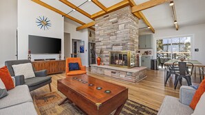 A spacious living room with a stone fireplace, wooden beams, a flat-screen TV, and comfortable seating. - Mid Century Modern home in the boulders. Amazing views. 1 mile from downtown. (Prescott)