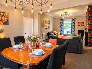 A dining area with a wooden table set for four, surrounded by chairs.