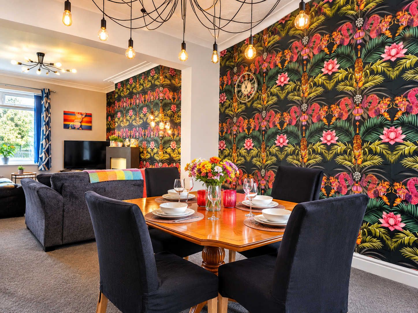 A dining area with a round table set for four, surrounded by dark upholstered chairs.