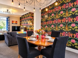 A dining area with a round table set for four, surrounded by dark upholstered chairs.