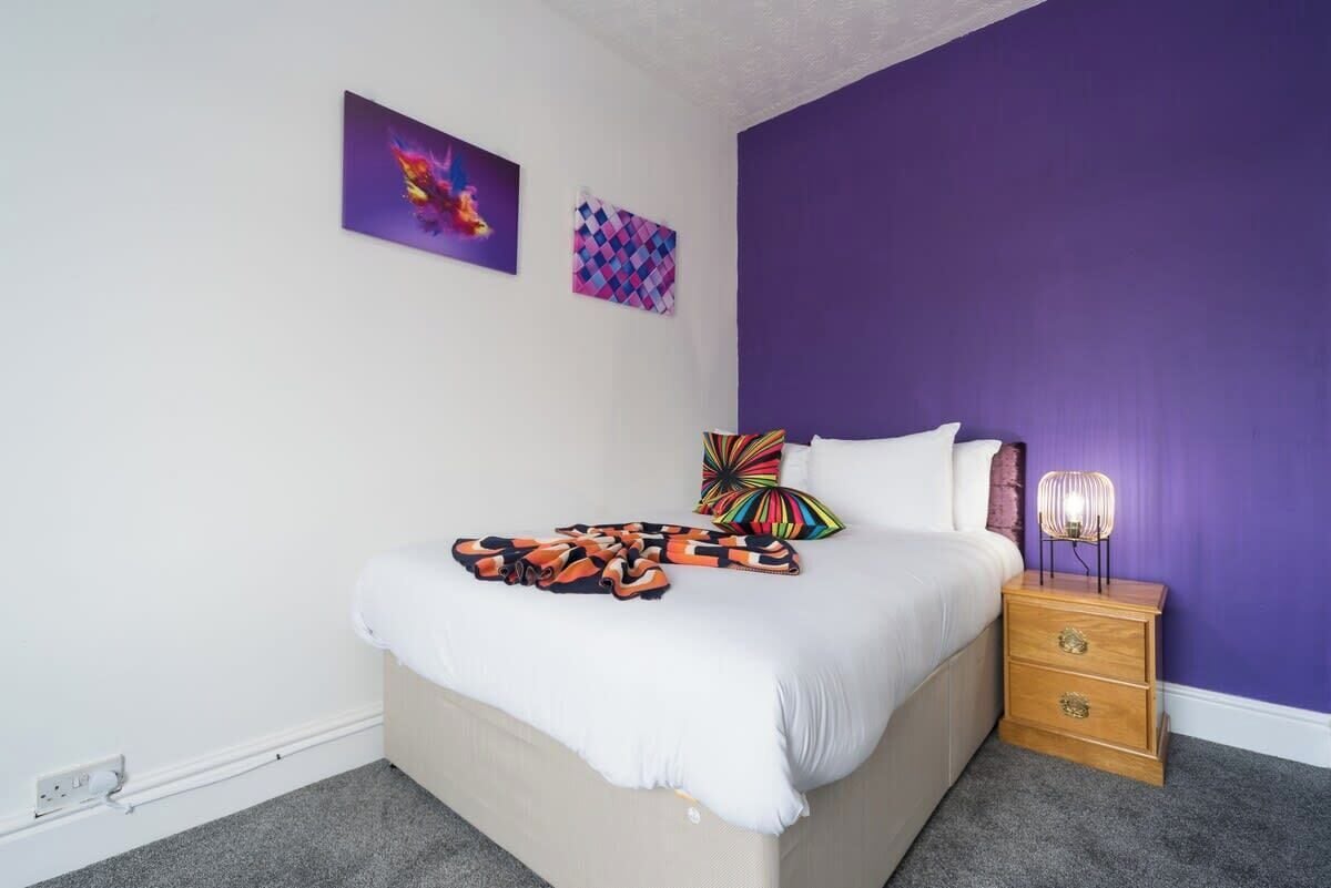 Una camera da letto con un letto, un comodino e una parete decorata con due opere d'arte.