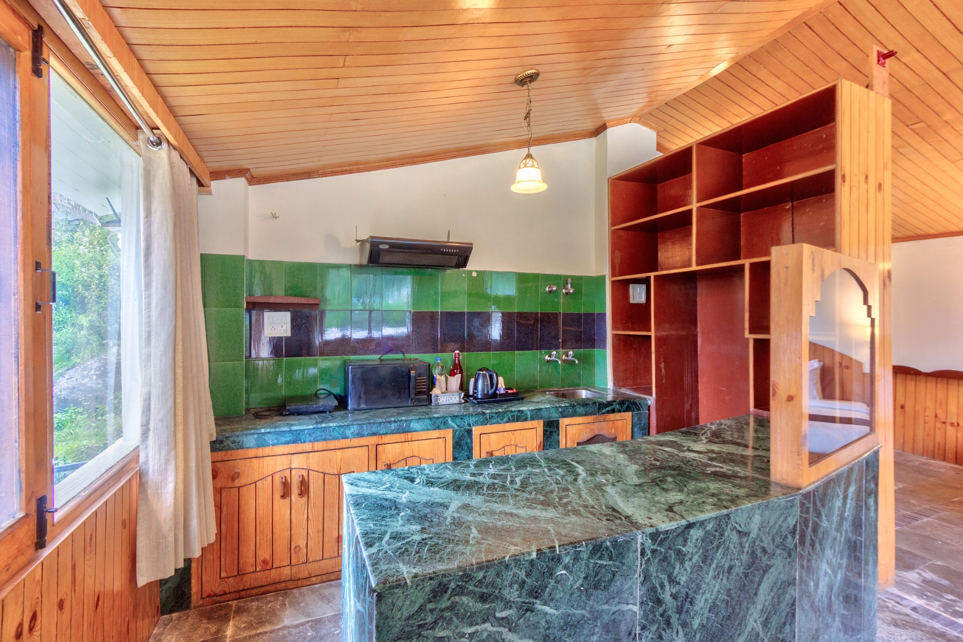 A kitchen with wooden cabinets, a marble countertop, and green tiled backsplash.