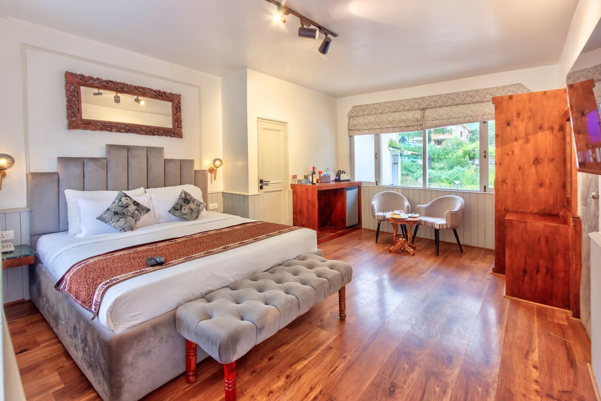 A bedroom with a large bed, a bench, a desk, and a chair.