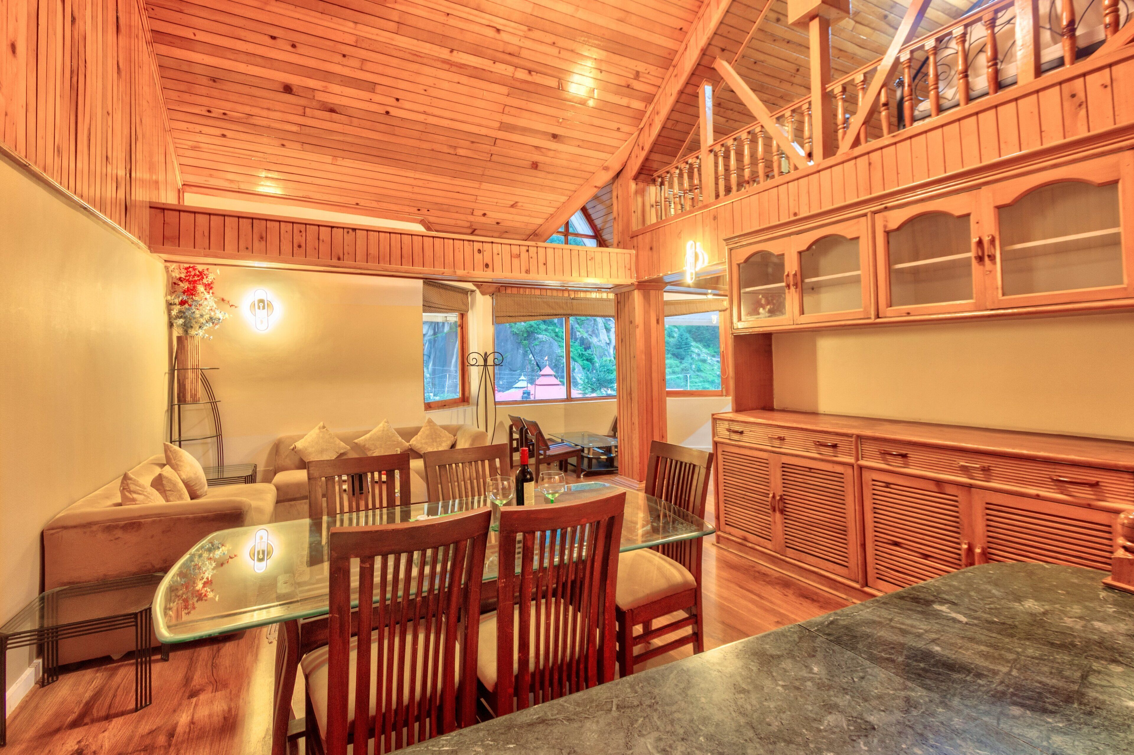 A wooden interior with a dining area, a sofa, and a kitchen with wooden cabinets.
