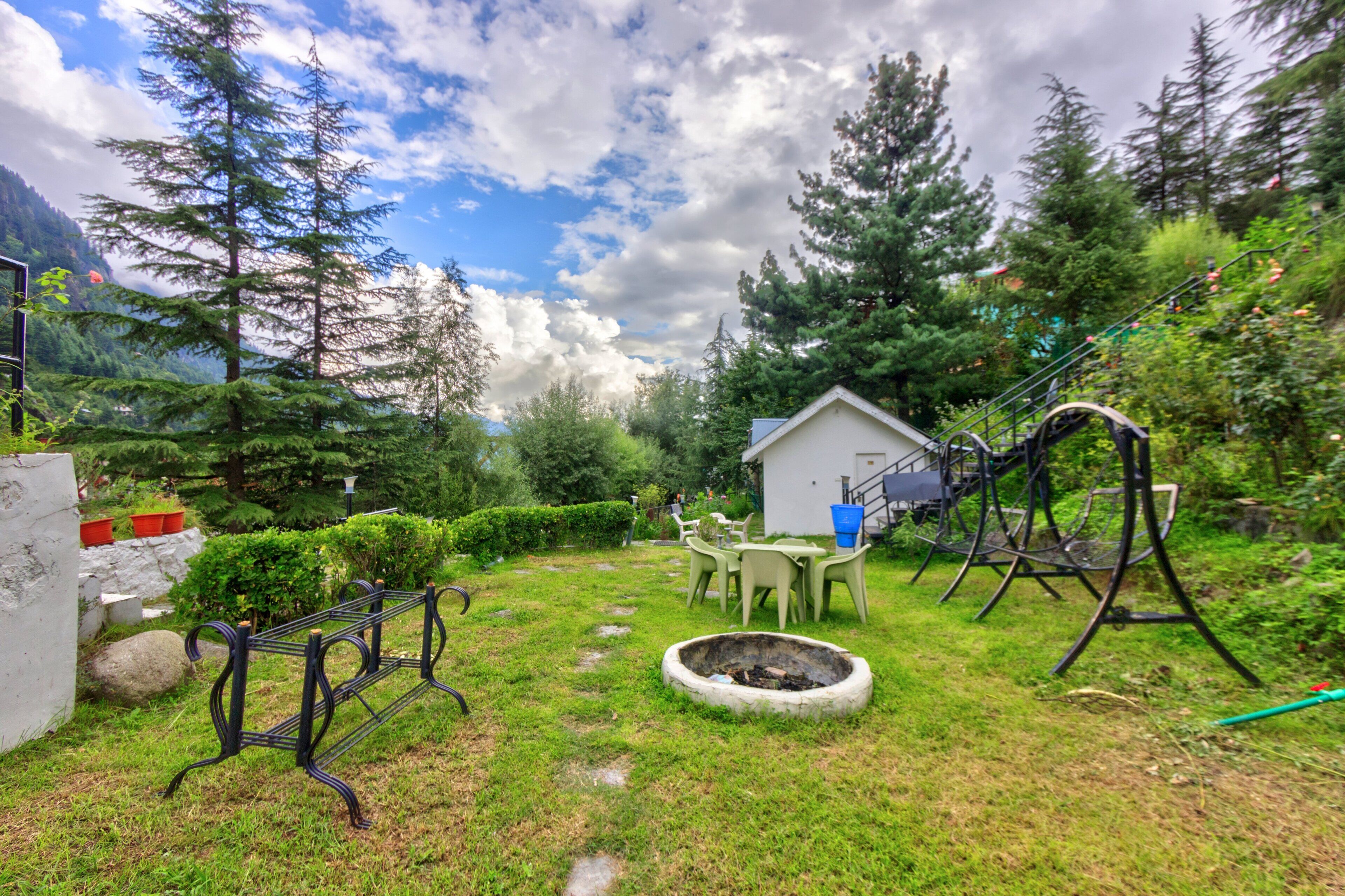 A garden with a wooden bench, a small shed, and a fire pit.