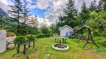 A garden with a wooden bench, a small shed, and a fire pit.
