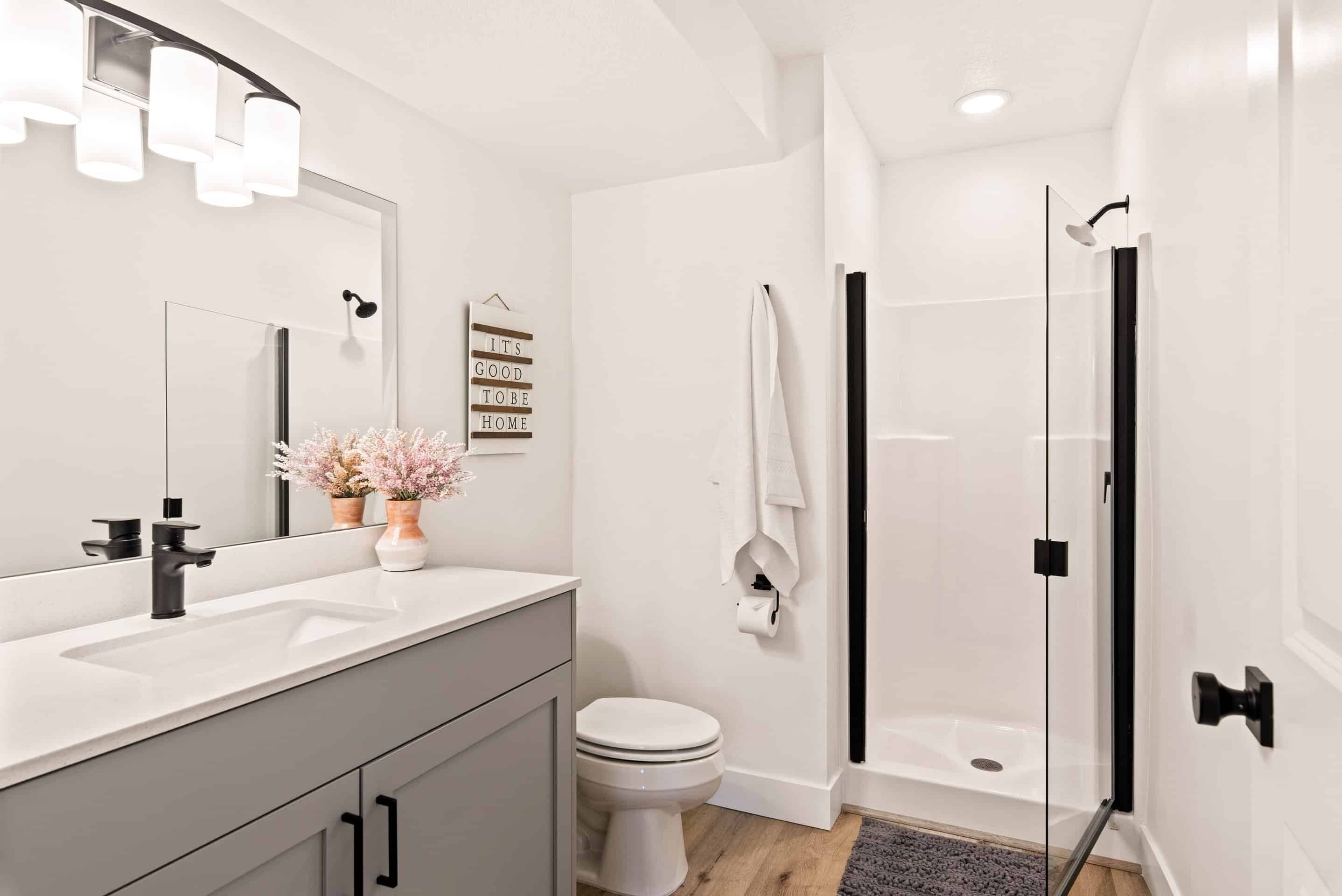 Un baño moderno con lavamanos blanco, inodoro y ducha con mampara de vidrio.