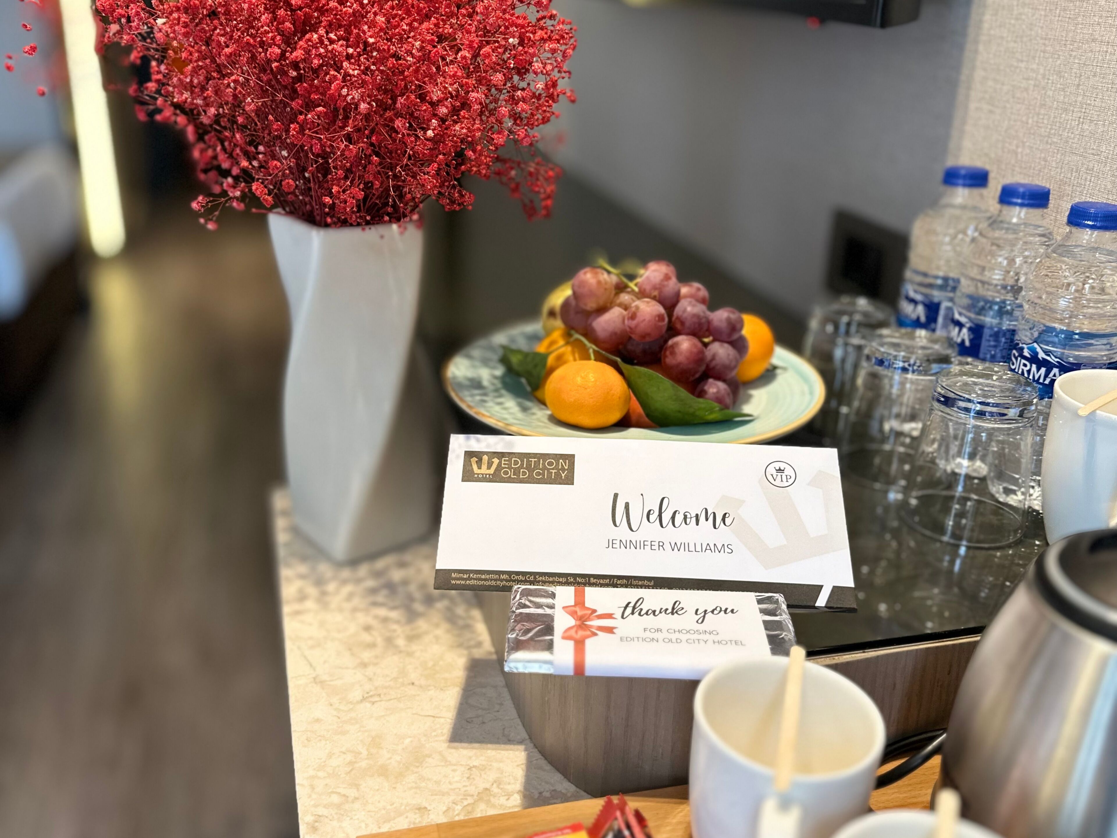 A welcome sign with a guest's name, a thank you note, and a fruit plate.