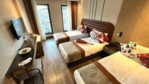 Ein Hotelzimmer mit zwei Betten, einem Schreibtisch, einem Sessel und einem Fernseher.