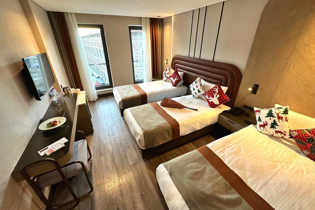 Une chambre d’hôtel avec deux lits, un bureau, une chaise et un téléviseur.