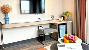 Ein modernes Hotelzimmer mit Flachbildfernseher, kleinem Kühlschrank, Spüle und Frühstückstresen.