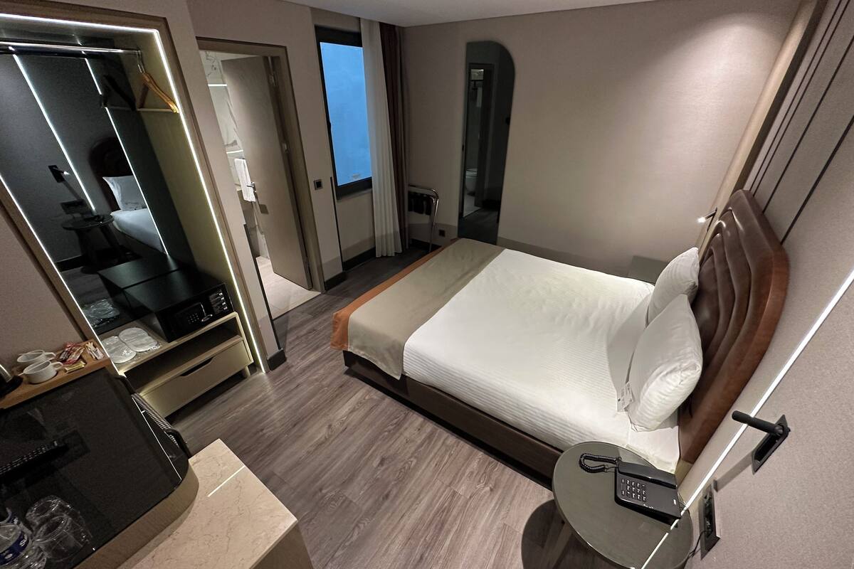 Une chambre d’hôtel avec un lit, une table de chevet, un miroir et une vue sur l’extérieur.