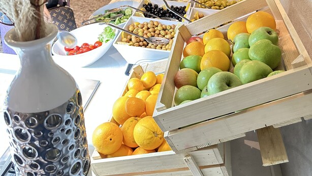 Ein reichhaltiges Buffet mit verschiedenen Speisen, darunter Obst und Gemüse, sowie eine dekorative Vase mit Trockenpflanzen.