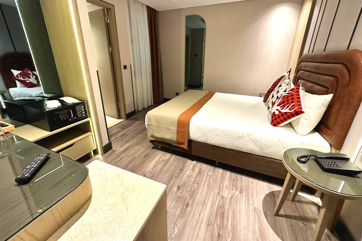 Une chambre d’hôtel comprenant un lit, une table de chevet et un bureau avec un téléphone.
