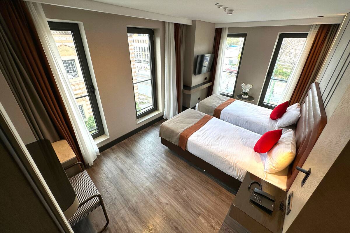 Une chambre d’hôtel avec deux lits, une télévision, un bureau et de grandes fenêtres.