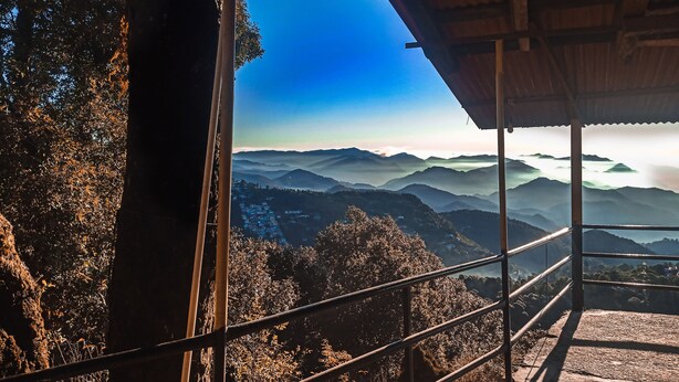 Une vue depuis un balcon abrité, donnant sur un paysage montagneux sous un ciel dégagé.