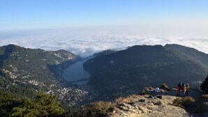Un paysage montagneux avec une vallée et une étendue d’eau. On peut voir des personnes debout sur un promontoire rocheux.