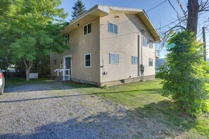A two-story building with a front porch, a garage, and a gravel driveway. - Honeoye Lake House w/ Community Amenities! (Honeoye)