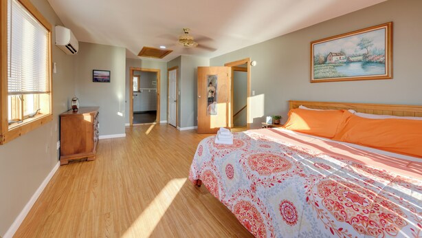 A bedroom with a bed, a dresser, a painting, and a hallway leading to another room. - Honeoye Lake House w/ Community Amenities! (Honeoye)