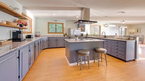 A modern kitchen with a large island, grey cabinets, wooden flooring, and pendant lighting. - Honeoye Lake House w/ Community Amenities! (Honeoye)