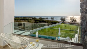 A balcony with a glass railing overlooking a grassy area and the sea. - Villa Pelagia - Sea Front Villa Pelagia (Sfakia)