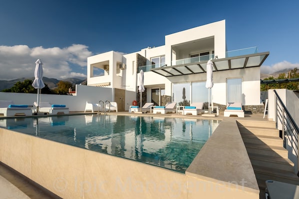 A modern poolside area with lounge chairs and a clear pool.
