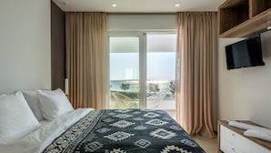 A bedroom with a bed, a TV, and a balcony with curtains. - Villa Pelagia - Sea Front Villa Pelagia (Sfakia)
