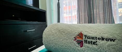 A hotel room with a bed, a television, and a window with curtains.