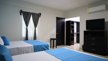 Habitación de hotel con dos camas, un televisor, un armario y una puerta que da a otra habitación.
