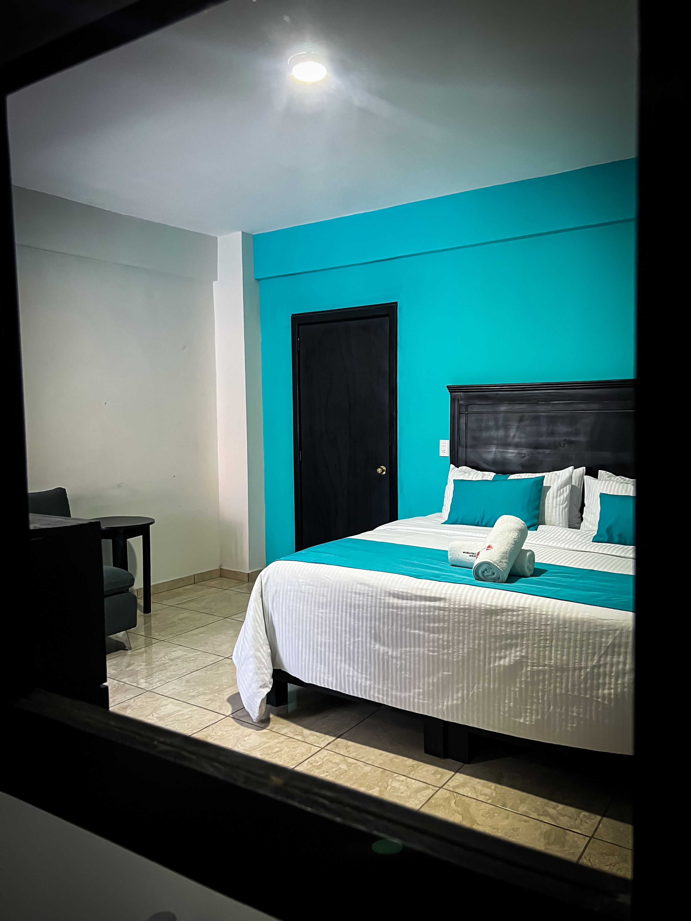 A hotel room with a bed, a desk, and a door.