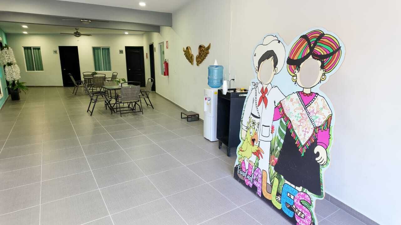 Een hotel lobby met een receptiebalie, een waterkraan en een zithoek met tafels en stoelen.